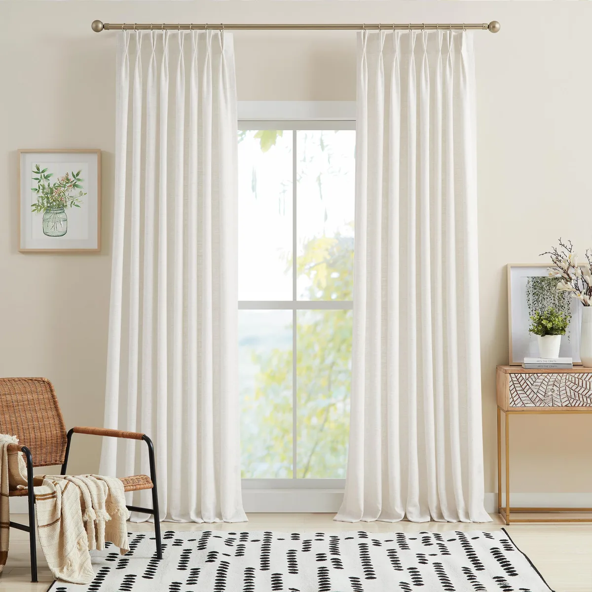 White pinch-pleat Lesley panels covering a full wall behind a light wood dining table with rattan chairs