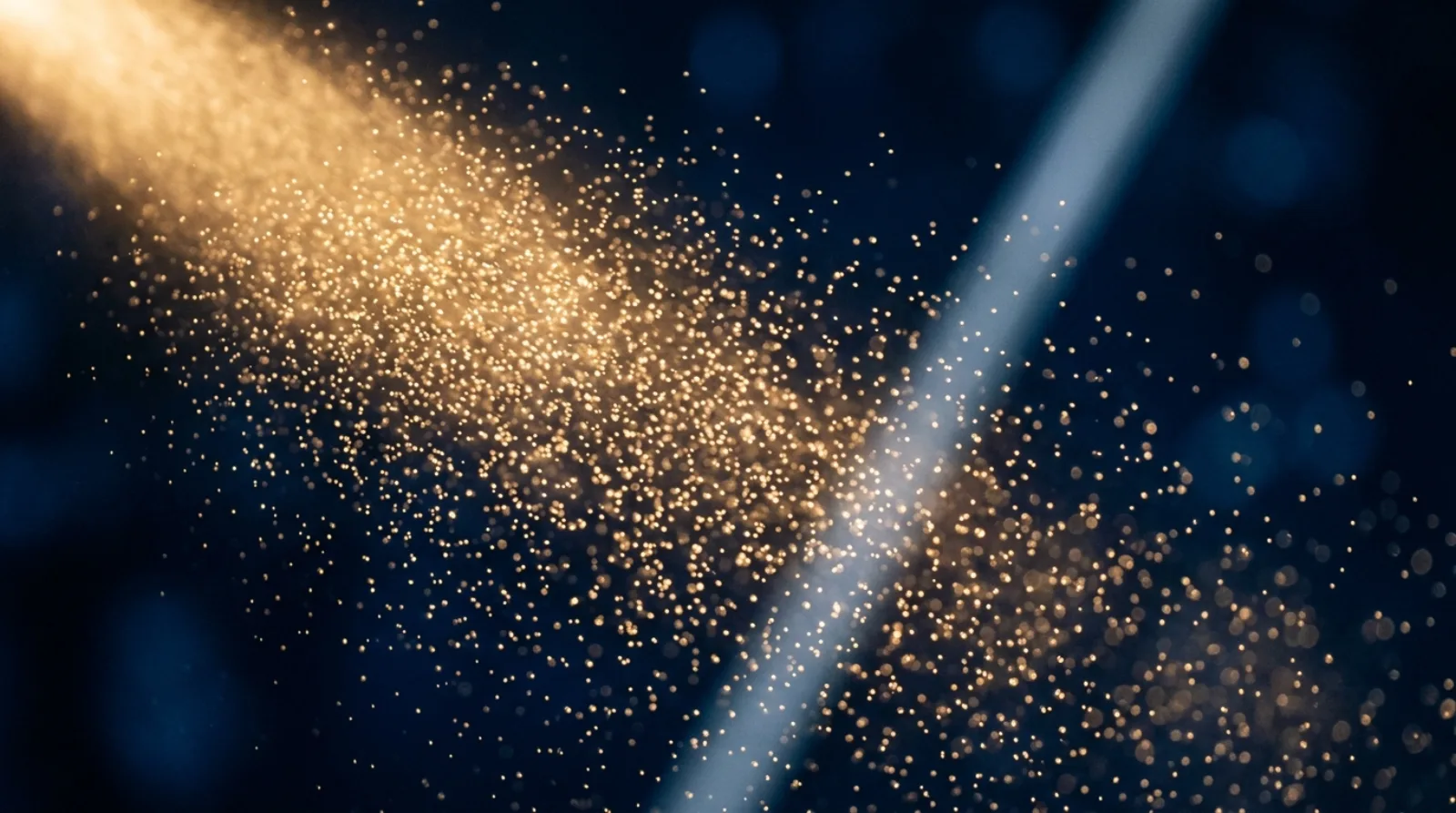 Extreme macro of fine water mist droplets glowing in warm lamplight against deep blue darkness, a thin band of cool moonlight crossing the frame