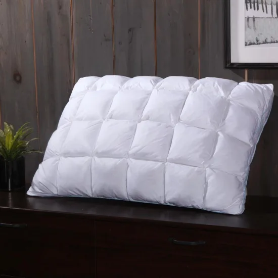 A white goose down pillow with French pleats standing on a dark wood dresser against a grey wood wall