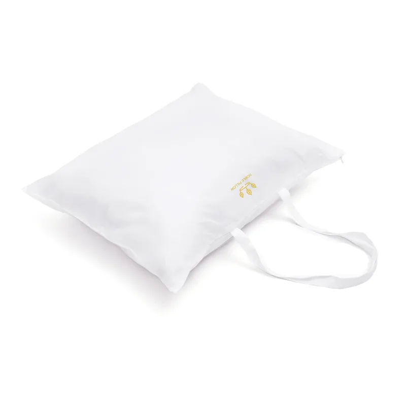 A head pillow inside a white travel bag with two handles and a zipper, Noble Pillow embroidered in gold thread, on a white background