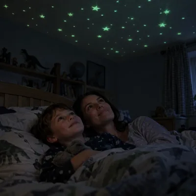 A mother and her young son lie on a bed, smiling up at glow-in-the-dark stars on the bedroom ceiling