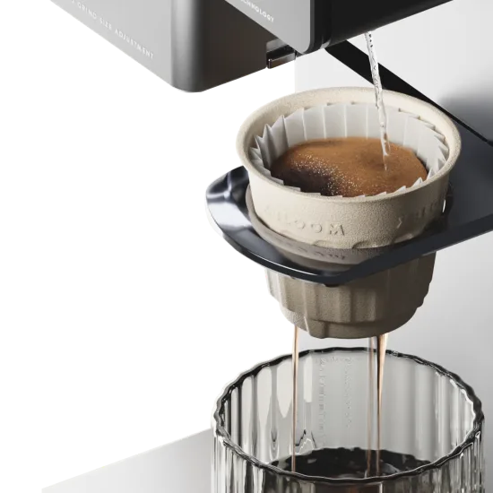 Water streaming from the xBloom spout onto freshly ground coffee swelling inside the xPod's paper filter, two streams dripping into a ribbed glass