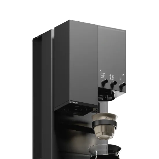 Close-up of the top of the xBloom Studio: the lit dot display above three knobs, the xbloom mark on the grinder housing and an xPod on the dock below
